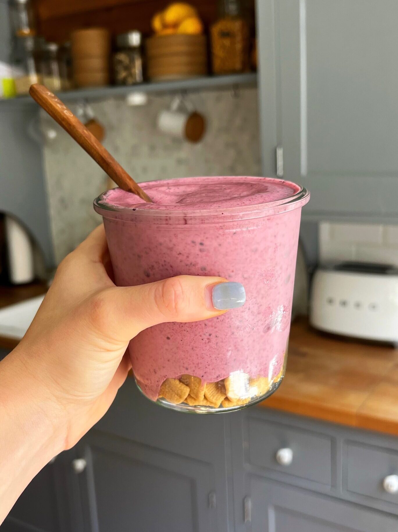 A side view of the berry cheesecake smoothie being held with a hand