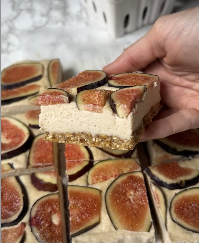 image of a hand holding the NO BAKE VEGAN MAPLE AND FIG CHEESECAKE BARS up close