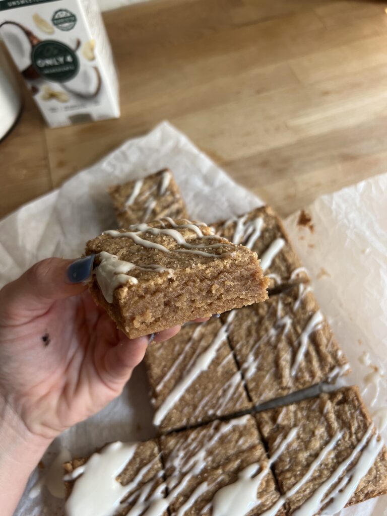 Image of cinnamon roll blondie being help to show the inside and texture.